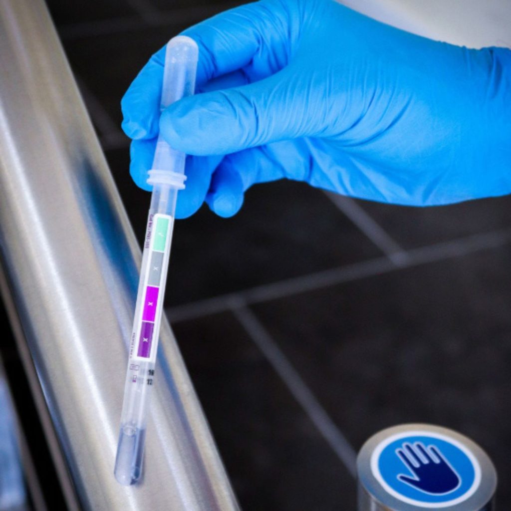 A blue-gloved hand holding a swab