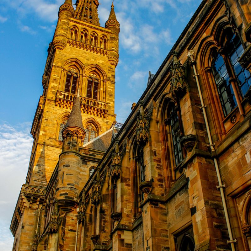 A vertical shot of University of Glasgow on blue cloudy sky background in Scotland
